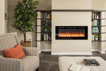 A living room with a fireplace, a chair, a couch, and a tree.